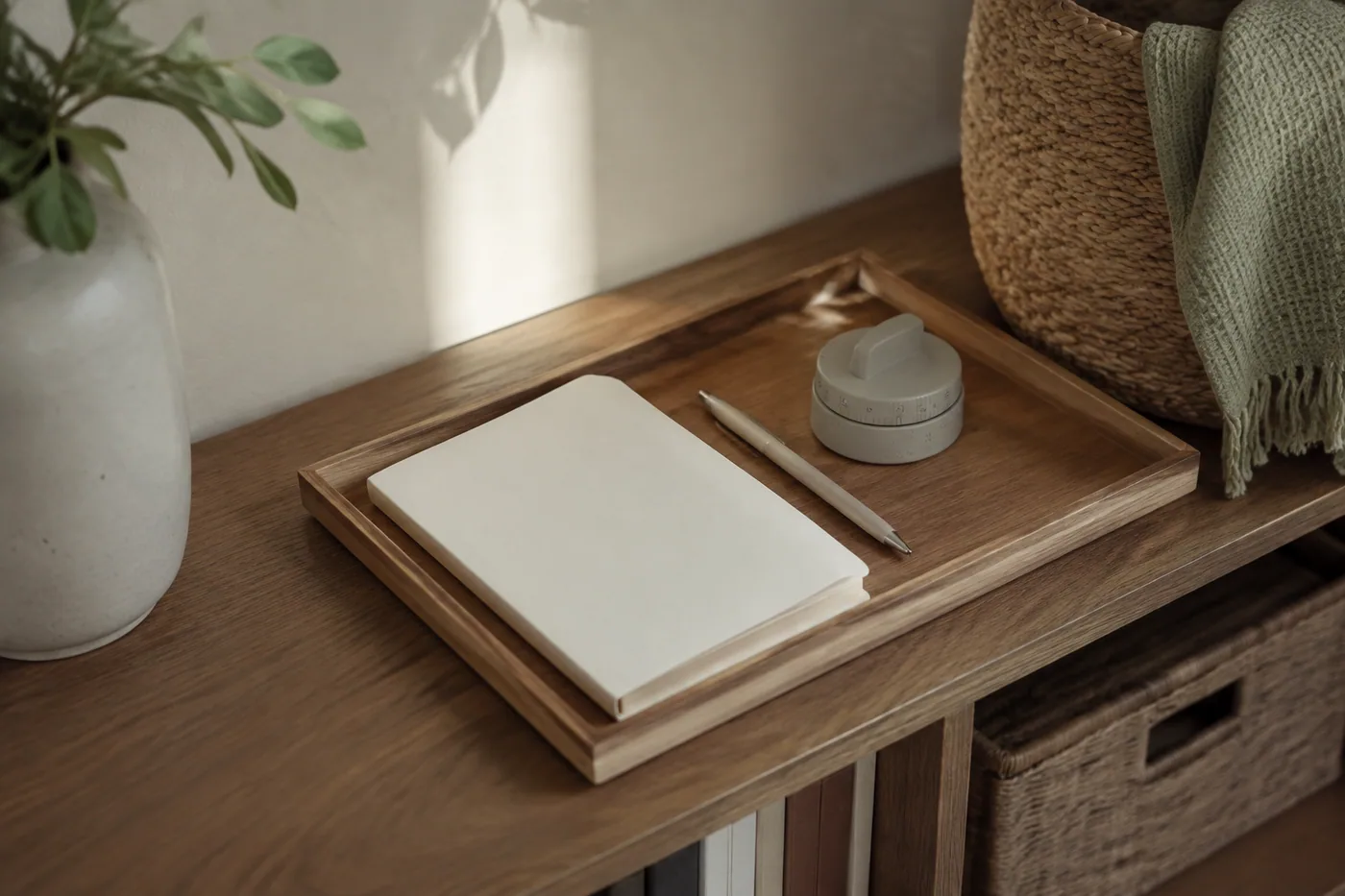 A wooden tray holding a notebook, pen, and kitchen timer on a shelf.